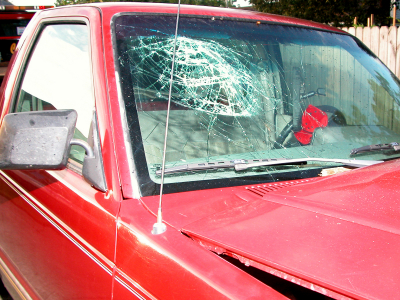 A red truck with its windshield smashed in.