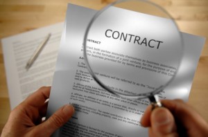 A person holding a magnifying glass over a contract.