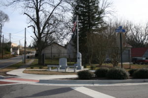 A street corner with two benches and trees.