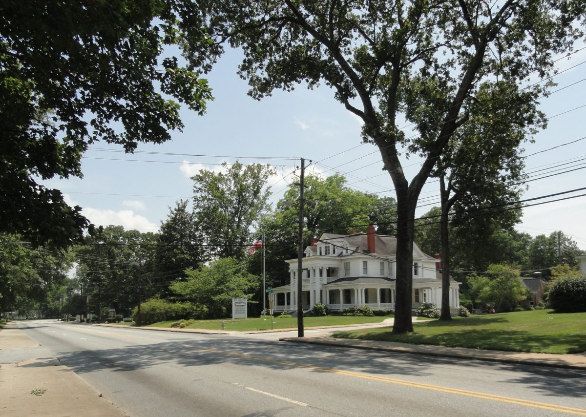 A large white house sitting on the side of a road.