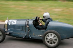 A person in an old car driving down the road.