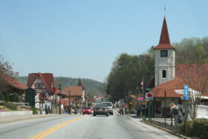 A street with cars driving down it and people walking on the sidewalk.