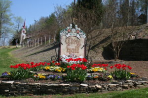 A sign in the middle of a flower garden.