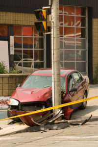 A red car that is sitting on the side of a pole.