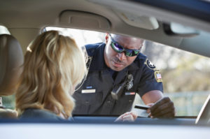 A police officer is talking to a woman in the back of his car.