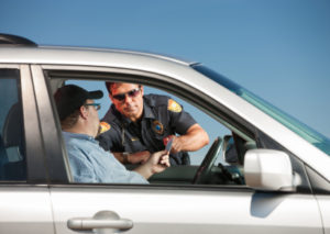 A police officer talking to a man in the drivers seat of his car.