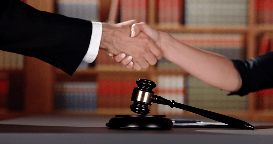 Handshake over gavel in legal setting.