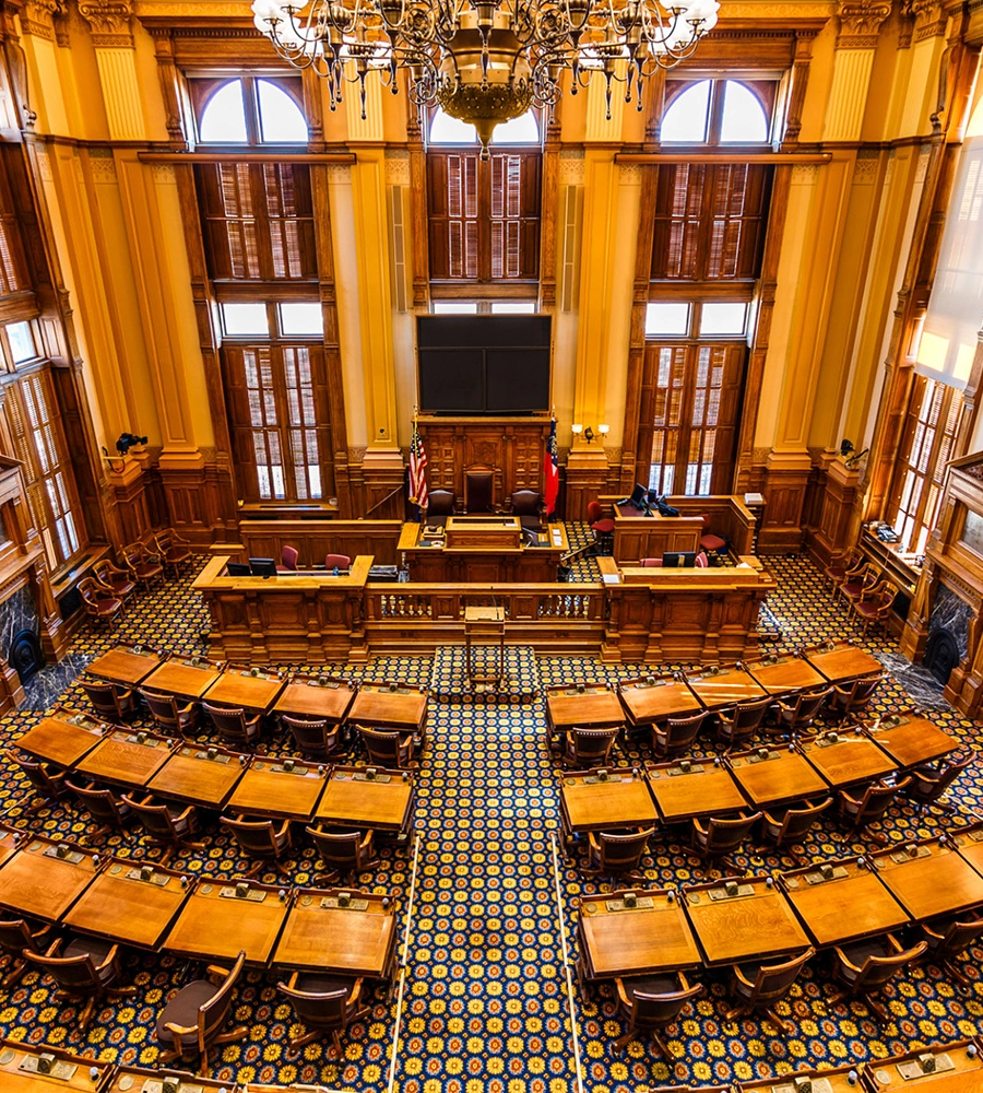 Ornate legislative chamber with wooden desks.